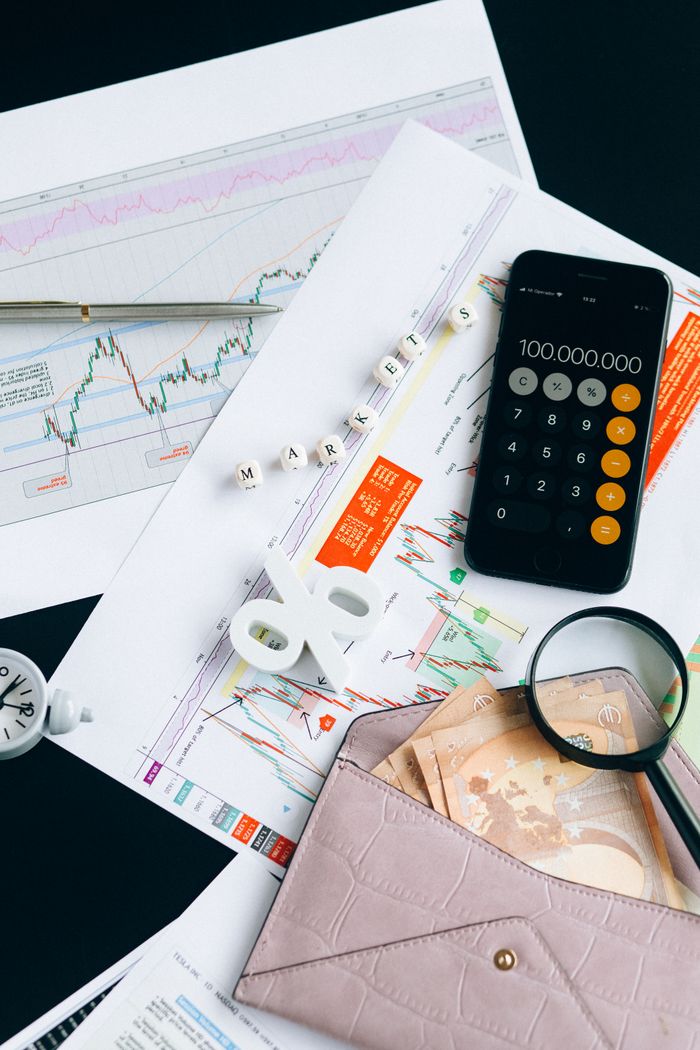 our-story Flat lay of financial charts, smartphone calculator, and documents for market analysis.