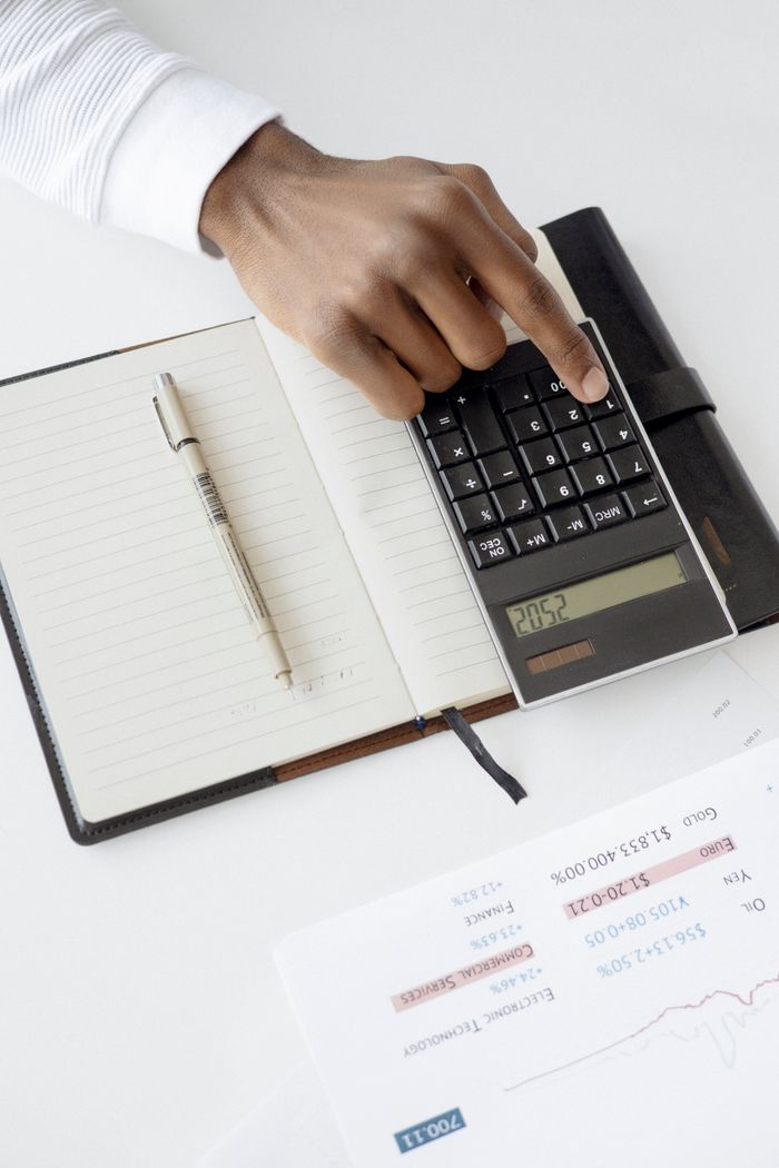 services-01 A hand using a calculator with financial documents and notebook, depicting an office setup for financial analysis.
