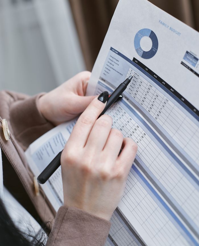 about-us Hands holding a pen review a family budget document with graphs and tables.